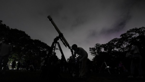 A girl looks at the moon through a telescope in Caracas, Venezuela, on Sunday, May 15, 2022. The best day to spot five planets, Mercury, Jupiter, Venus, Uranus and Mars, lined up in the night sky is Tuesday, March 28, 2023, right after sunset. The five-planet array will be visible from anywhere on Earth, as long as you have clear skies. (AP Photo/Matias Delacroix)