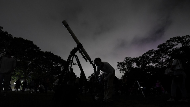A girl looks at the moon through a telescope in Caracas, Venezuela, on Sunday, May 15, 2022. The best day to spot five planets, Mercury, Jupiter, Venus, Uranus and Mars, lined up in the night sky is Tuesday, March 28, 2023, right after sunset. The five-planet array will be visible from anywhere on Earth, as long as you have clear skies. (AP Photo/Matias Delacroix)