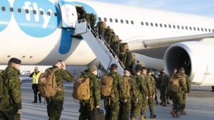 Members of the 5e Regiment d'artillerie legere du Canada board an aircraft heading for Latvia, in Quebec City, Wednesday, March 23, 2022. The Canadian Armed Forces is under fire for its plan to cut thousands of troops off a cost-of-living allowance without much notice. THE CANADIAN PRESS/Jacques Boissinot