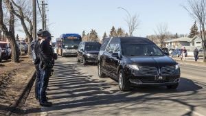 Police salute during a procession to a funeral home for Const. Travis Jordan and Const. Brett Ryan in Edmonton on Tuesday, March 21, 2023. A regimental funeral is set to be held Monday for the two officers, who were shot and killed while responding to a family dispute. (THE CANADIAN PRESS/Jason Franson)