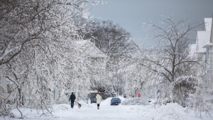 People walk along an ice covered street after a winter storm in Fort Erie, Ont., Tuesday, Dec. 27, 2022. THE CANADIAN PRESS/Nick Iwanyshyn