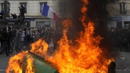 Demonstrators walk past burning garbage cans during a demonstration Tuesday, March 28, 2023 in Paris. It's the latest round of nationwide demonstrations and strikes against unpopular pension reforms and President Emmanuel Macron's push to raise France's legal retirement age from 62 to 64. (AP Photo/Thibault Camus)