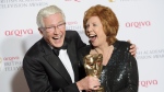 FILE - British presenters Paul O'Grady, left, and Cilla Black joke with her Special Award at the British Academy Television Awards at a central London venue, Sunday, May 18, 2014. Entertainer Paul O’Grady, who achieved fame as drag queen Lily Savage before becoming a much-loved comedian and host on British television, has died. He was 67. (Photo by Jonathan Short/Invision/AP, File)