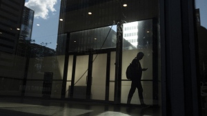 A man walks though a downtown Toronto office building with other buildings reflected in a window in this June 11, 2019 photo. The future of Canada's social safety net is pending after the federal budget made no mention of employment insurance reform, despite the Liberals having promised to modernize the program. THE CANADIAN PRESS/Graeme Roy
