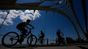 FILE - Cyclists enjoy the outdoors on a hot day as they ride across the Humber Bay Bridge in Toronto on Thursday, June 23, 2022. THE CANADIAN PRESS/Nathan Denette 