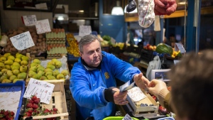 József Varga, owner of a grocery in Budapest's Grand Market Hall, sells vegetables on Saturday, April 8, 2023. Varga says his wholesale costs have risen by 20% to 30%. All his customers have noticed the price spikes — some more than others. (AP Photo/Denes Erdos)