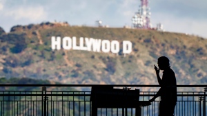 A worker wheels equipment past the famous Hollywood sign as preparations continue on March 8, 2023, for the 95th Academy Awards at the Dolby Theatre in Los Angeles.  (AP Photo/J. David Ake, File)