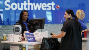 A Southwest airlines customer service representative, left, assists a traveler at the ticketing counter at Love Field airport, Friday, May 19, 2023, in Dallas. The unofficial start of the summer travel season is here, with airlines hoping to avoid the chaos of last year and travelers scrounging for ways to save a few bucks on pricey airfares and hotel rooms.(AP Photo/Tony Gutierrez)
