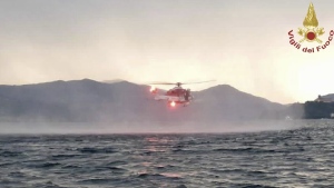 In this image released by the Italian firefighters a helicopter search for missing after a tourist boat capsized in a storm on Italy's Lago Maggiore in the northern Lombardy region, Sunday, May 28, 2023, with at least one person confirmed dead. Authorities were searching for several people who were still missing after a sudden whirlwind overturned a boat carrying more than 20 tourists and crew. (Vigili Del Fuoco via AP)
