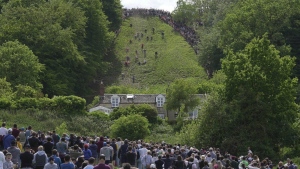 Participants compete in the downhill race during the Cheese Rolling contest at Cooper's Hill in Brockworth, Gloucestershire, Monday May 29, 2023. The Cooper's Hill Cheese-Rolling and Wake is an annual event where participants race down the 200-yard (180 m) long hill chasing a wheel of double gloucester cheese. (AP Photo/Kin Cheung)
