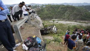 People watch as a rescue team inspects the wreckage after a bus carrying Hindu pilgrims to a shrine skid off a highway bridge into a Himalayan gorge near Jammu, India, Tuesday, May 30, 2023. (AP Photo/Channi Anand)
