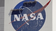 FILE - Workers on scaffolding repaint the NASA logo near the top of the Vehicle Assembly Building at the Kennedy Space Center in Cape Canaveral, Fla., May 20, 2020. (AP Photo/John Raoux, File)