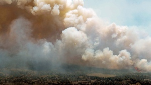 An aircraft (centre) disperses a mix of water and fire retardant over a fire near Barrington Lake in Shelburne County, N.S., in this Wednesday, May 31, 2023 handout photo. More than 300 firefighters from the United States and South Africa are heading to Canada in the coming days as the country battles an unprecedented wildfire season. THE CANADIAN PRESS/HO-Communications Nova Scotia