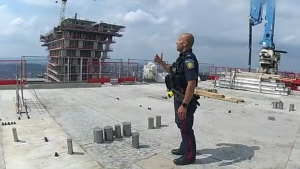 Peel police officer urges man standing on the edge of the roof of a highrise building in Mississauga to take a step back. (Peel Regional Police)