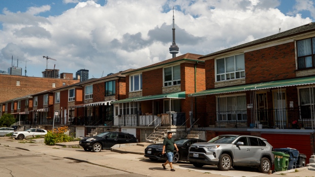A person walks by a row of houses in Toronto, Tues. July 12, 2022. THE CANADIAN PRESS/Cole Burston 