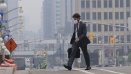 A man walks to work wearing a mask near Parliament Hill, Wednesday, June 7, 2023 in Ottawa. The battle against hundreds of wildfires continued Thursday, as almost every jurisdiction in Canada was under either heat or air quality warnings from the federal government. THE CANADIAN PRESS/Adrian Wyld
