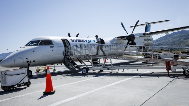 A passenger boards a WestJet Encore Bombardier Q400 twin-engined turboprop aircraft in Kamloops, Saturday, June 3, 2023. WestJet and Swoop pilots ratified their collective agreement after a bargaining process that saw the threat of a strike snarl many Canadians' long weekend plans. THE CANADIAN PRESS/Jeff McIntosh
