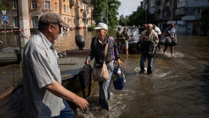 Alyona Shkrygalova carries her bags after evacuating from a flooded neighborhood on the left bank of the Dnipro river in Kherson, Ukraine, Friday, June 9, 2023. In Ukraine, the governor of the Kherson region, Oleksandr Prokudin, said Friday that water levels had decreased by about 20 centimeters (8 inches) overnight on the western bank of the Dnieper, which was inundated starting Tuesday after the breach of the Nova Kakhovka dam upstream. (AP Photo/Evgeniy Maloletka)