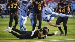 Toronto Argonauts quarterback Chad Kelly (12) scores while being tackled by Hamilton Tiger-Cats defensive back Tunde Adeleke (2) during first half CFL action against the Hamilton Tiger-Cats in Toronto on Sunday, June 18. THE CANADIAN PRESS/Christopher Katsarov