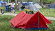 A man makes his way through a tent encampment in a city park in Toronto on Tuesday May 25, 2021. 
