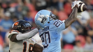 Toronto Argonauts defensive back Tarvarus McFadden (20) makes an interception over BC Lions wide receiver Dominique Rhymes (19) during first half CFL action in Toronto on Monday, July 3, 2023. THE CANADIAN PRESS/Frank Gunn