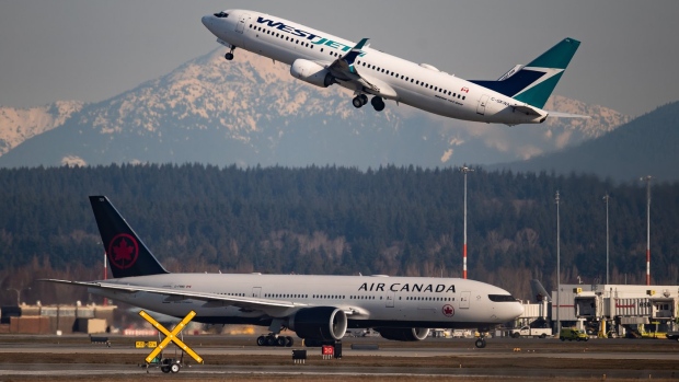 Figures from an aviation data firm show Canada's two biggest airlines see a far higher proportion of their flights delayed compared with many of their peers abroad. An Air Canada flight taxis to a runway as a WestJet flight takes off at Vancouver International Airport, in Richmond, B.C., on March 20, 2020. THE CANADIAN PRESS/Darryl Dyck