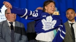 Easton Cowan puts on a Toronto Maple Leafs jersey after being picked by the team during the first round of the NHL hockey draft Wednesday, June 28, 2023, in Nashville, Tenn. The Leafs have signed Cowan to a three-year, entry-level contract.THE CANADIAN PRESS/AP-George Walker IV