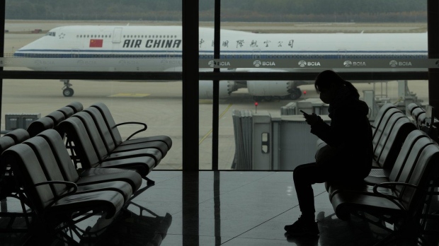 Beijing and Ottawa are in talks over how to increase flights between Canada and China, following an American deal in June. A passenger checks her phone as an Air China passenger jet taxis past at the Beijing Capital International airport in Beijing, Saturday, Oct. 29, 2022. THE CANADIAN PRESS/AP-Ng Han Guan