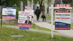 More Canadians are co-owning homes with family members or friends, a recent Royal LePage survey shows. A person walks past multiple for-sale and sold real estate signs in Mississauga, Ont., on Wednesday, May 24, 2023. THE CANADIAN PRESS/Nathan Denette