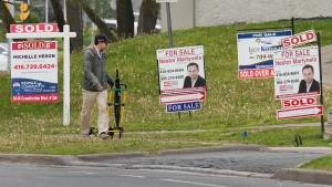 A person walks past multiple for-sale and sold real estate signs in Mississauga, Ont., on Wednesday, May 24, 2023. THE CANADIAN PRESS/Nathan Denette 