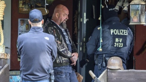 Sven Krueger, left, a right-wing extremist known throughout Germany, stands between police officers during a search operation on his property in Jamel, Germany, Tuesday, Sept. 19, 2023. Germany has banned the neo-Nazi group Hammerskins Germany and is raiding homes of dozens of its members. The group is an offshoot of an American right-wing extremist group and plays a prominent role across Europe. Interior Minister Nancy Faeser said on Tuesday the ban is a "hard blow against organized right-wing extremism.” (Jens Buettner/dpa via AP)
