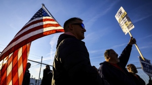 UAW members Dan Schlieman, with flag, and Brad Geer work the picket line during a strike Tuesday, Sept. 19, 2023, at the Stellantis Toledo Assembly Complex where Jeeps are made in Toledo, Ohio. (Jeremy Wadsworth/The Blade via AP)