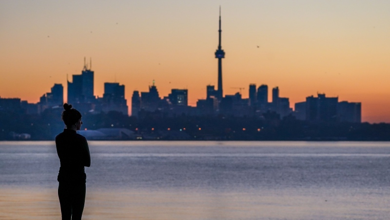 In this file photo, a woman looks out at the Toronto skyline from Sheldon Lookout during sunrise in Toronto on Friday, November 5, 2021. THE CANADIAN PRESS/Evan Buhler