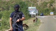A Kosovo police officer guards the road near the village of Banjska, 55 kilometers (35 miles) north of the capital Pristina, northern Kosovo, Sunday, Sept. 24, 2023. Prime Minister Albin Kurti on Sunday said one police officer was killed and another wounded in an attack he blamed on support from neighboring Serbia, increasing tensions between the two former war foes at a delicate moment in their European Union-facilitated dialogue to normalize ties. (AP Photo/Dejan Simicevic)