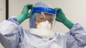 A health-care professional adjusts her mask during a demonstration of Personal Protective Equipment (PPE) procedures at Toronto Western Hospital on Friday, October 17, 2014. Canada has approved a vaccine to prevent Ebola in non-pregnant and otherwise healthy adults aged 18 and over following exposure to the virus in this country.THE CANADIAN PRESS/Chris Young