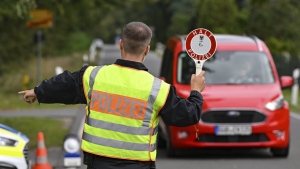 A police officer stops a car during a check against smuggling during the police's efforts to combat smuggling and illegal immigration, in Roggosen, Germany, Monday, Sept. 25, 2023. More than 350 German federal police searched premises across the country in connection with smuggling of migrants early on Tuesday. (Patrick Pleul/dpa via AP)
