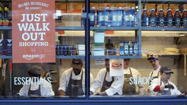 In this Jan. 22, 2018, file photo, workers as seen from a sidewalk window as they assemble sandwiches in an Amazon Go store in Seattle. Toronto and Calgary sports fans will soon be able to skip the lineup when purchasing snacks before or during games. The Scotiabank Arena in Toronto and Scotiabank Saddledome in Calgary are rolling out Amazon technology allowing some of the venue’s stores to offer fans checkout-free shopping. THE CANADIAN PRESS/AP/Elaine Thompson