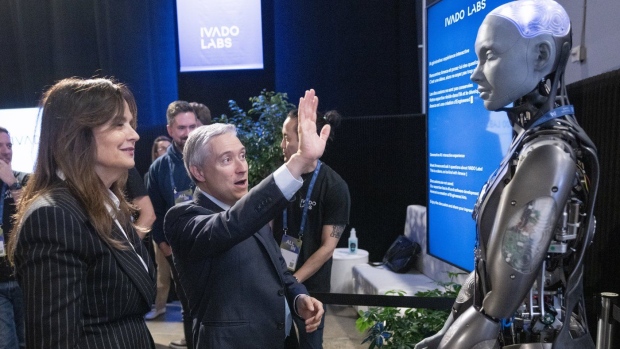 Federal Industry Minister Francois-Philippe Champagne says hello to an AI robot as Helene Desmarais, executive chairwoman, of IVADO Labs looks on at the All In artificial intelligence conference Wednesday, September 27, 2023 in Montreal.THE CANADIAN PRESS/Ryan Remiorz