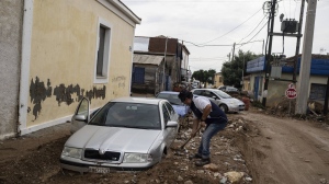 Theodoros Tamvakis 62 shovels mud outside his damaged car following floods in the town of Agria near the city of Volos, Greece, Thursday, Sept. 28, 2023. A second powerful storm in less than a month hammered parts of central Greece Thursday, sweeping away roads, smashing bridges and flooding thousands of homes. (AP Photo/Petros Giannakouris)