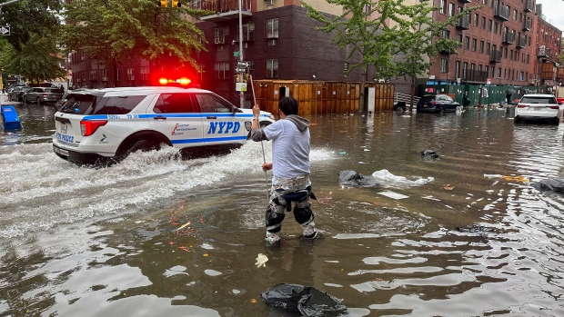 A man works to clear a drain in flood waters, Friday, Sept. 29, 2023, in the Brooklyn borough of New York. A potent rush-hour rainstorm has swamped the New York metropolitan area. The deluge Friday shut down swaths of the subway system, flooded some streets and highways, and cut off access to at least one terminal at LaGuardia Airport. (AP Photo/Jake Offenhartz)
