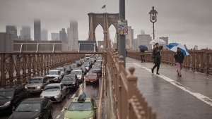 People hold umbrellas as cars move along along Brooklyn Bridge following heavy rains on Friday, Sept. 29, 2023, in New York. (AP Photo/Andres Kudacki)
