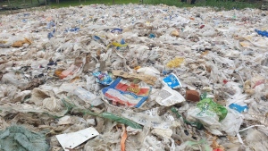 Plastic food packaging waste sits on top of a pile of garbage that was dumped in the streets and empty greenspaces in Shwepyithar, Myanmar, in an undated photo.