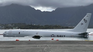 A Navy P-8A plane that overshot a runway at Marine Corps Base Hawaii and landed in shallow water offshore sits on a reef and sand in Kaneohe Bay, Hawaii, on Monday, Nov. 27, 2023. The U.S. Navy said Monday that it has removed nearly all of the fuel from the large plane that landed in an environmentally sensitive bay, but it doesn't have a timetable for when it will get the aircraft out of the water. (AP Photo/Audrey McAvoy)