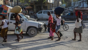 People, who were displaced from their homes due to clashes between armed gangs in Cite Soleil, walk down a street in the Tabarre neighborhood as they seek refuge in Port-au-Prince, Haiti, Wednesday, Nov. 15, 2023. (AP Photo/Odelyn Joseph)