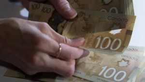 An Interac survey shows 40 per cent of Canadians are concerned that they could fall victim to a financial scam. Canadian $100 bills are counted in Toronto, Feb. 2, 2016. THE CANADIAN PRESS/Graeme Roy