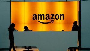 FILE - In this Feb. 14, 2019 file photo, people stand in the lobby for Amazon offices in New York. Amazon finally has its answer to ChatGPT. The tech giant said Tuesday, Nov. 28, 2023, it will launch Q – a generative-AI powered chatbot for businesses. (AP Photo/Mark Lennihan, File)