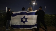 People holding an Israeli flag watch the arrival of a helicopter transporting Israeli hostages released by Hamas at Ichilov hospital in Tel Aviv Tuesday Nov. 28, 2023. Hamas and Israel released more hostages and prisoners under terms of a fragile cease-fire that held for a fifth day Tuesday. (AP Photo/Leo Correa)
