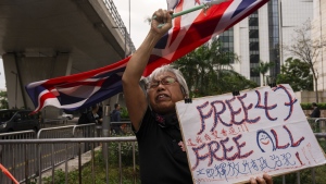 A pro-democracy activist known as "Grandma Wong" protests outside the West Kowloon courts in a cordoned off area set up by police as closing arguments open in Hong Kong's largest national security trial of 47 pro-democracy figures in Hong Kong, Wednesday, Nov. 29, 2023. (AP Photo/Louise Delmotte)
