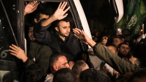 Men wave after being released from prison by Israel, in the West Bank town of Ramallah, early Thursday, Nov. 30, 2023. International mediators on Wednesday worked to extend the truce in Gaza, encouraging Hamas militants to keep freeing hostages in exchange for the release of Palestinian prisoners and further relief from Israel's air and ground offensive. (AP Photo/Nasser Nasser)