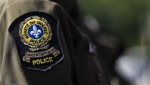A Surete du Quebec emblem is seen on an officer's uniform in Montreal, Tuesday, Aug. 22, 2023. Quebec provincial police say they have arrested 26 men as part of a provincewide anti-child pornography operation. THE CANADIAN PRESS/Christinne Muschi